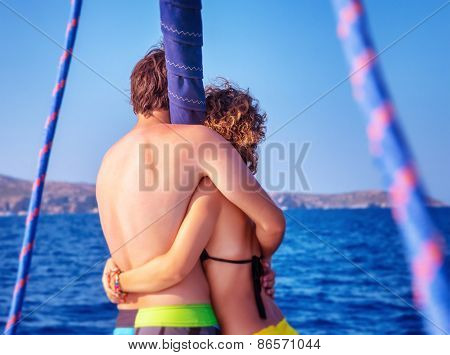 Back side of happy couple in love traveling on luxury sail boat along sea, romantic honeymoon vacation, summer travel and tourism 