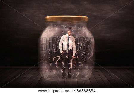 Businessman locked into a jar with question marks concept on background