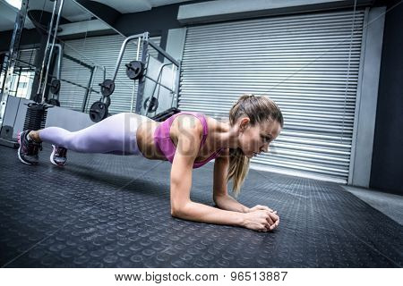 Side view of a muscular woman on a plank position