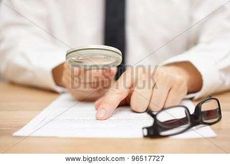 Focused Businessman Is Reading Through  Magnifying Glass Document