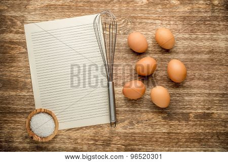 Eggs with beater and salt on wooden table