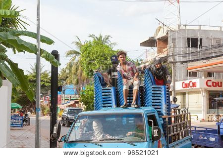 Guys ride in the back of the truck on blue plastic chairs