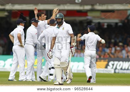 LONDON, ENGLAND. AUGUST 19 2012 South Africa's Hashim Amla walks off after being dismissed as England celebrate in the background during the third  test match between England and South Africa