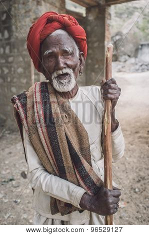 GODWAR REGION, INDIA - 13 FEBRUARY 2015: Blind Rabari tribesman holds stick in courtyard. Post-processed with grain, texture and colour effect.