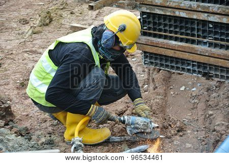 Construction workers using construction grinder to sharpen steel at construction site