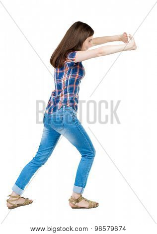 back view of woman pushes wall. Isolated over white background. Rear view people collection. backside view person. young girl in checkered blue with red stripes leaning trying to move something in law