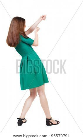back view of standing girl pulling a rope from the top or cling to something. girl  watching.  Isolated over white background. The girl in stylish green dress pulling a rope from the top-right.