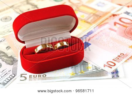 Wedding rings in box  on banknotes background. Marriage of convenience
