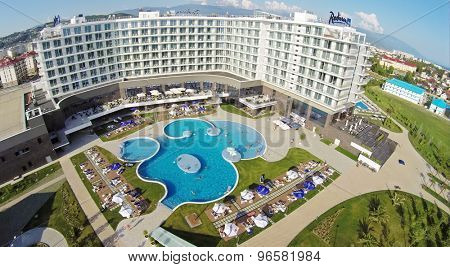 RUSSIA, SOCHI - JUL 25, 2014: Tourists get rest around and in pool of hotel Radisson Blu at summer sunny day. Aerial view. Photo with noise from action camera.