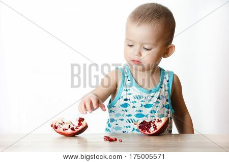 Baby eats a pomegranate ripe and juicy very tasty and joyfully