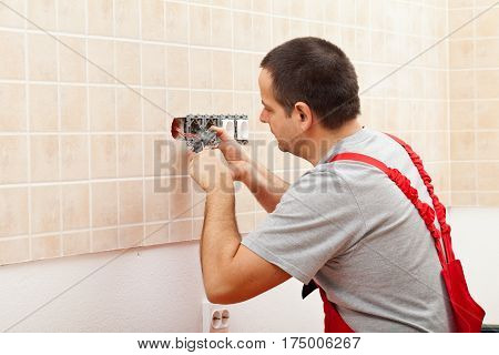 Electrician installing electrical wall fixture - fastening the wires in the receptacle