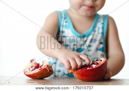 Baby eats a pomegranate ripe and juicy very tasty and joyfully