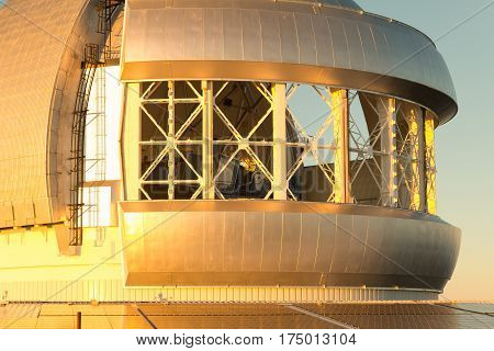 Close up of Gemini observatory with open wind vents on Maunakea volcano on the Big Island of Hawaii. Photo lightly desaturated to remove some of the intense reflected color cast from the sunset.