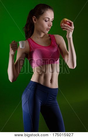 Caucasian girl that chooses to eat sports nutrition or apple. Choice concept.