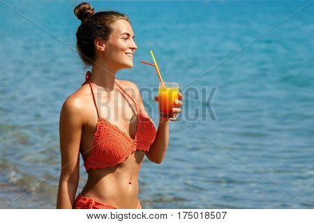 Beautiful woman on the beach with a glass of cocktail