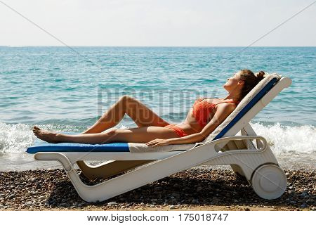 Beautiful woman is lying on the sunbed and enjoying of her vacation at the beach
