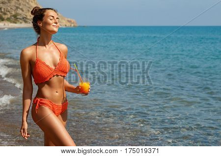 Beautiful woman on the beach with a glass of cocktail