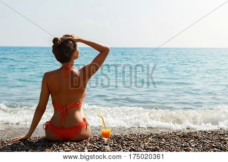 Beautiful woman on the beach with a glass of cocktail