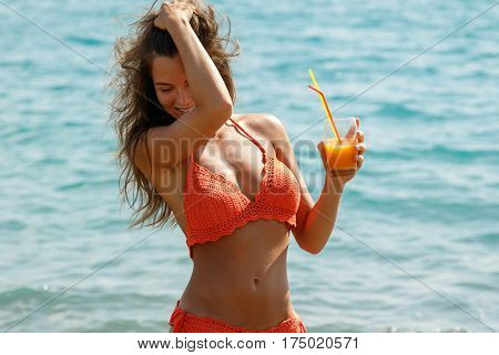 Beautiful woman on the beach with a glass of cocktail