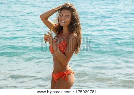 Beautiful woman on the beach with a glass of cocktail