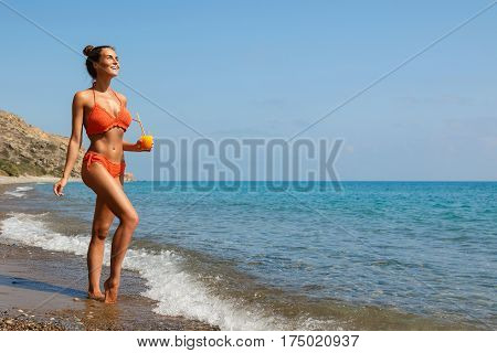Beautiful woman on the beach with a glass of cocktail