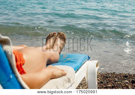 Female legs over sundbed and the sea