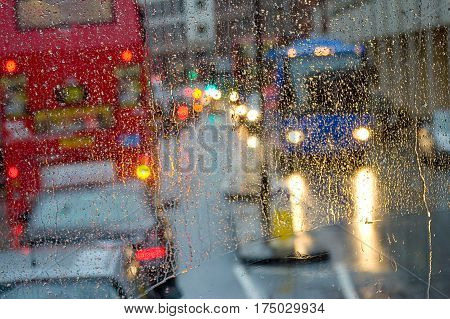 London rain view to red bus through rain-specked window