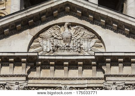 A close-up of the Phoenix sculpture which is located on the southern facade of St. Pauls Cathedral in London. The phoenix can be seen rising from the flames with the inscription RESVRGAM.