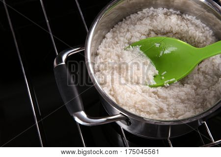Spoon with rice in metal pan on hotplate
