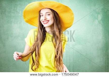 Colorful portrait of a beautiful woman in yellow t-shirt and hat on the green background