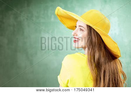 Colorful portrait of a beautiful woman in yellow t-shirt and hat on the green background
