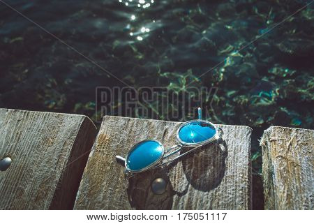 Concept of summer vacation with sunglesses on sea pier