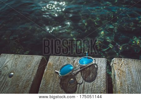 Concept of summer vacation with red striped socks and sunglesses on sea pier