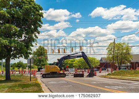 TWINSBURG OH - JULY 10 2016: A parked backhoe blocks access to an intersection in which a new roundabout is in initial stages of construction.