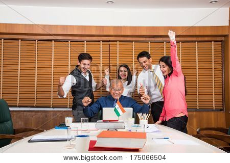 Indian business people enjoying success in conference room, either stock market or cricket or sports victory celebration in office