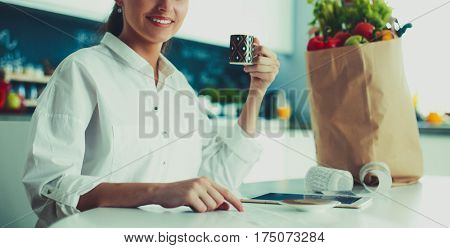 Young woman planning expenses and paying bills on her kitchen