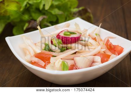 Fresh salad with cabbage, radish and tomato. Wooden background. Top view.