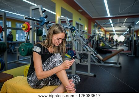 Young woman using phone in gym before exercises