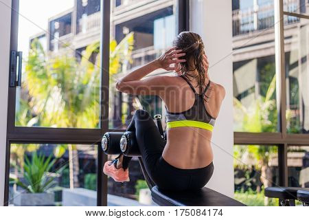 portrait of an athletic woman doing exercising abdominals work-out lying in gym at luxury hotel at summer.