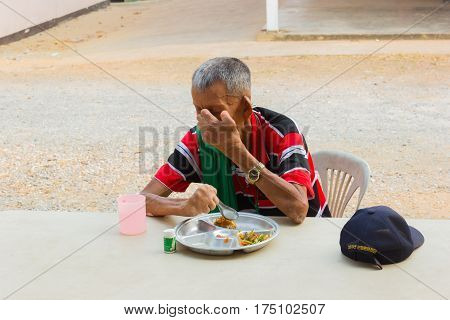 CHIANG RAI THAILAND - FEBRUARY 19 : unidentified old asian leprosy man with cap eating food on February 19 2016 in Chiang rai Thailand.