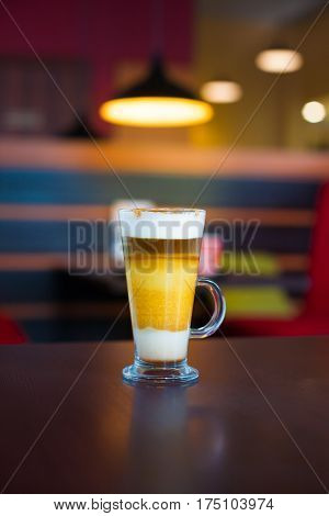 transparent mug with coffee machiato is on the table.
