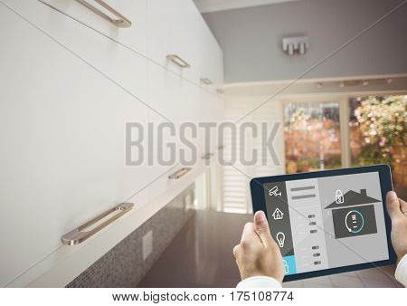Digital composite image of hands holding digital tablet with home security icons