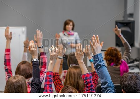 Diverse Group of Students in Conference Room raising Arms up actively participating in Seminar Teachers Body on background