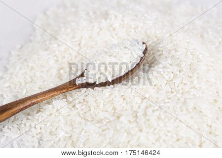 Rice grains closeup in a wooden spoon on the table