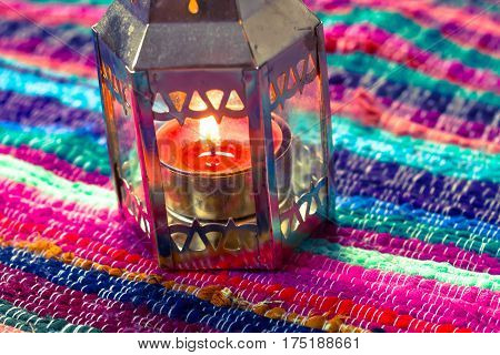 pink candle on a colorful handmade fabric .