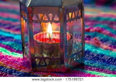 pink candle on a colorful handmade fabric .