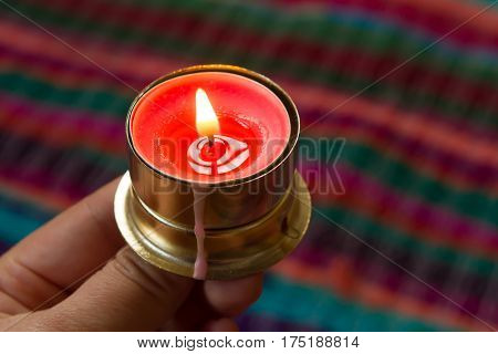 pink candle on a colorful handmade fabric .