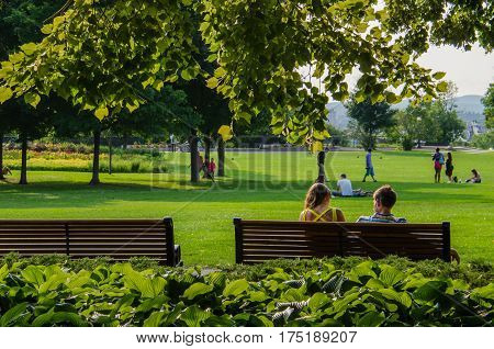 Ottawa, Canada - July 24, 2014: A couple relaxes on a bench framed by trees in Major's Hill Park in Ottawa, Canada.