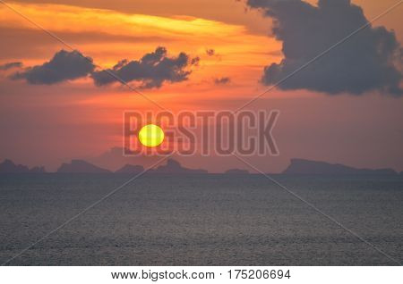 perfect sun hides behind clowds dramatic and colorful sunset at beach