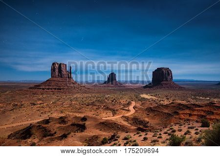 Classic panoramic view of scenic Monument Valley with the famous Mittens and Merrick Butte illuminated in beautiful mystic moonlight on a starry night in summer Arizona American Southwest USA